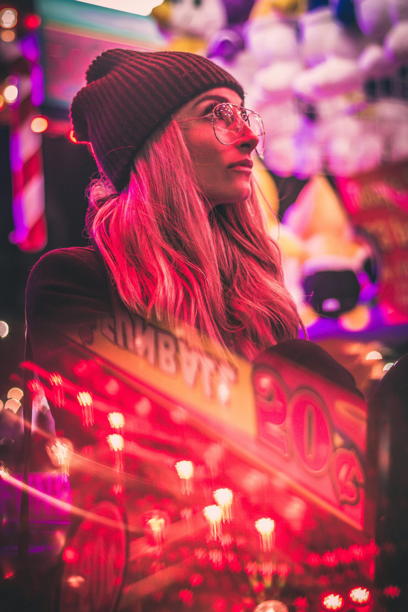 Stylish woman in urban setting with neon pink lights and casino reflections at night.